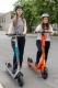 Two helmeted riders using e-scooters