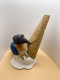 Une sculpture représente une glace fondue avec un oiseau perché dessus.