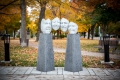 cement pillars hold a row of 4 aluminum sculptural faces