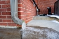 A downspout drains to an icy path in front of a house. 