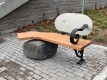 stylistic bench with a boulder under one side, wood to sit on and a metal backing
