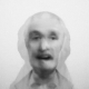 Black-and-white multiple-exposure portrait of two superimposed mens’ heads.