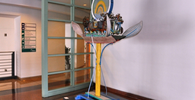 Sculpture on a pedestal of a ship with trees with wing-like oars under a rainbow in a circle