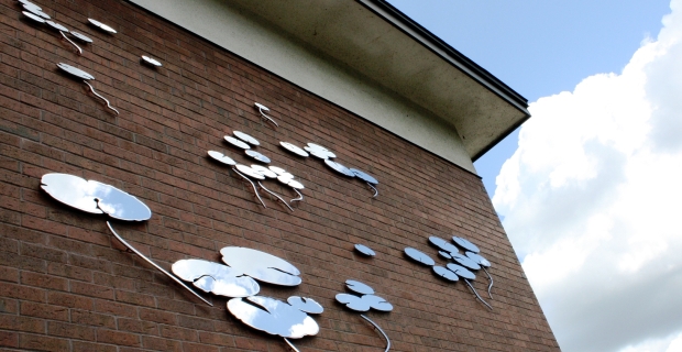 Metal silhouettes of water lilies attached to a brick building