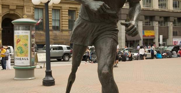 Sculpture of Terry Fox seemingly in motion, his strong right leg in front, his face and lagging artificial leg emphasize the struggle of the movement.
