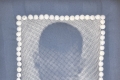 a multimedia artwork, blue and white in colour. The center of the artwork shows the back of a mans head. White, pearl-like embellishments form a frame around his head.