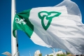 A close-up of the Franco-Ontarian flag flying against a clear blue sky.
