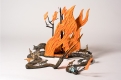 A sculpture of various animals fleeing a forest fire along two divergent pathways. The fire is bright orange and the animals are brown toned. A small blue house rests on one end of the pathway.