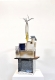 A metallic toned mixed-media sculpture sits on a white plinth, positioned against a white wall. 