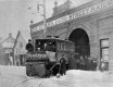 A streetcar sweeper coming out of the Railway building and surrounded by workers.