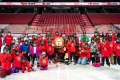 A group of children participating in the I Love to Skate program pose on the ice at the Canadian Tire Centre with Ottawa Senators ambassador of fun, Spartacat.