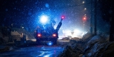 A snow plow, in the dark, with its lights on plowing a street while it is snowing. / Un chasse-neige éclairant de ses feux la rue à déneiger dans la nuit.