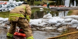 A firefighter installs a water pump in a flooded ditch