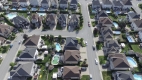  vue aérienne des maisons qui se ressemblent toutes avec l’herbe verte, les piscines et les rues partout