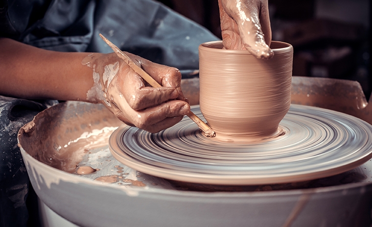 person making a pot on a pottery wheel