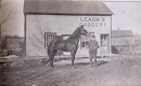 A man and a horse standing outside Leach's Store in North Gower