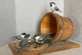 Five basswood hand-carved and painted chickadees eating seeds spilled from a pail. 