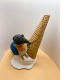 a sculpture depicts a melted ice cream cone with a bird perched atop it.