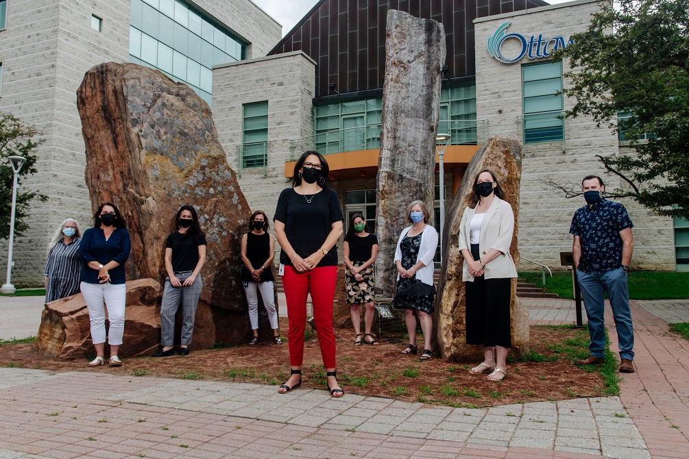 Eight women and one man stand distanced, wearing masks, outside Ottawa City Hall