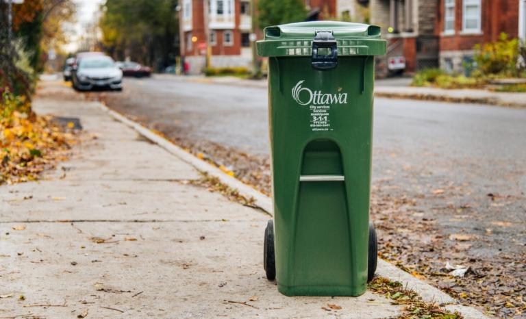 A city of Ottawa green bin on the curb, ready to be collected.