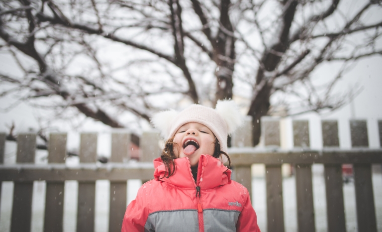 Jeune fille attrapant des flocons de neige avec sa langue