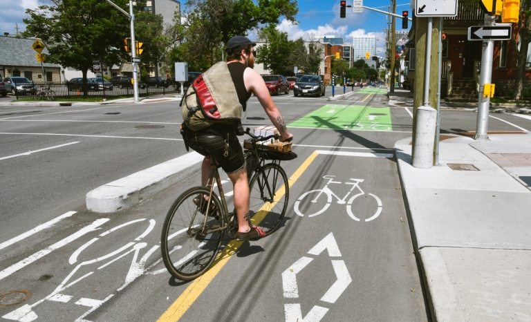 A cyclist in the summer travelling in a bike lane on O'Connor Street