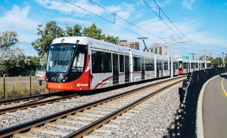 An LRT coming around a curve in the summer