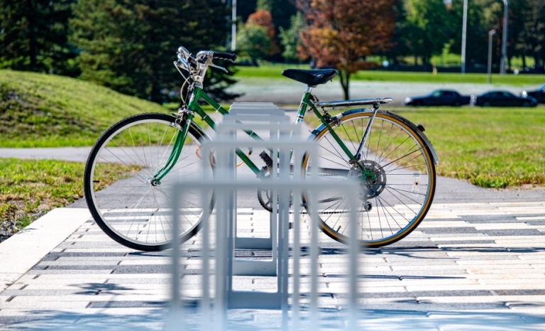 A bike locked up at a bike stand on a sunny day