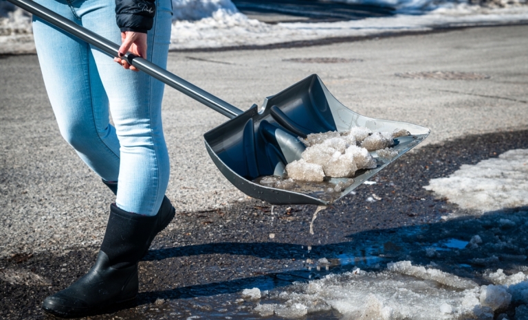 A resident clearing snow from a catch basin in the winter