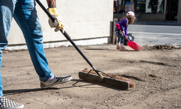 A grown up and child sweeping up debris