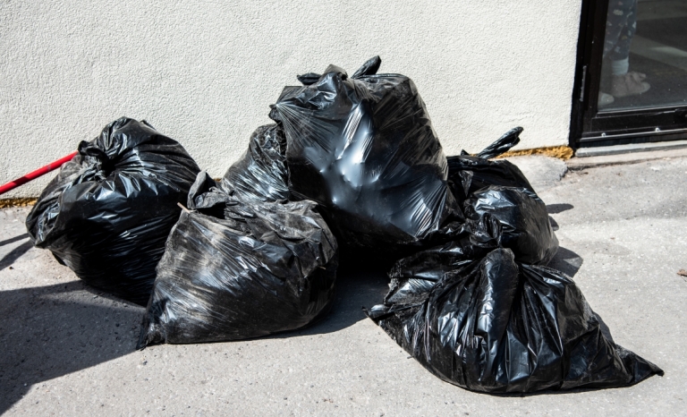 Five full garbage bags on the sidewalk