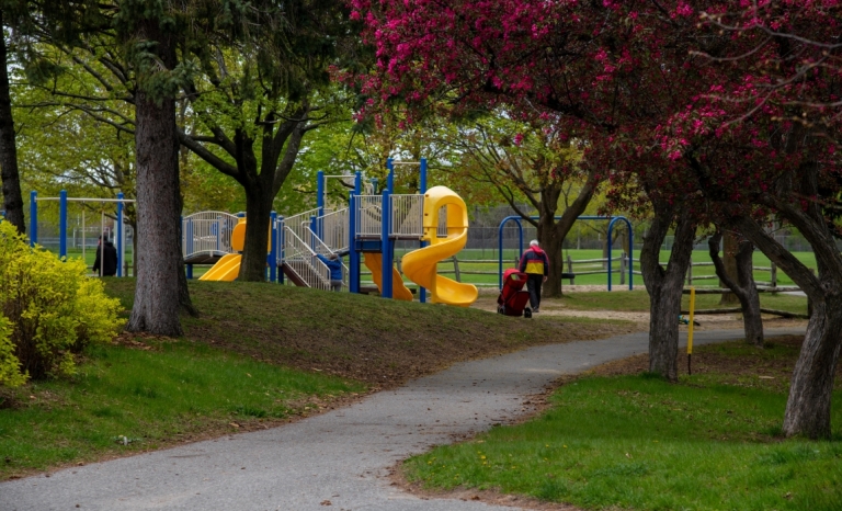 A walkway leading to a play structure in a wooden area at Craig Henry Park