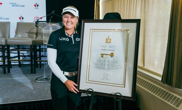 Golfer Brooke Henderson posing for a picture with her Key to the City plaque.