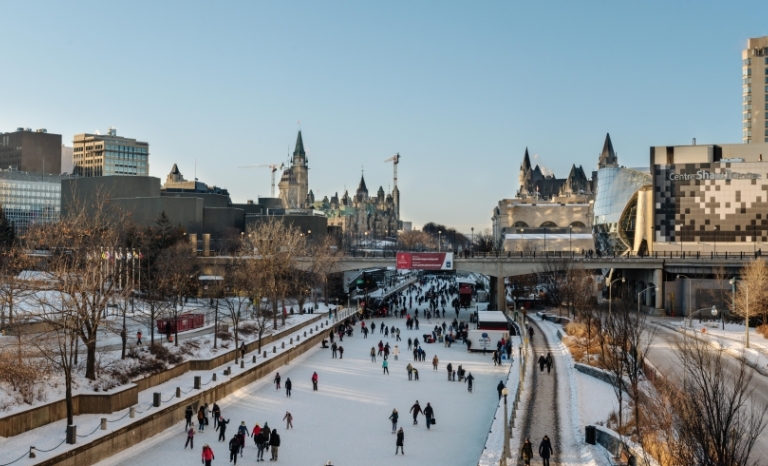 A panoramic view of the Rideau Canal in winter with many skaters and visitors