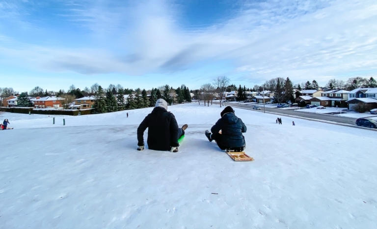 Deux lugeurs au sommet de la pente de glissade du parc Neil-Nesbitt