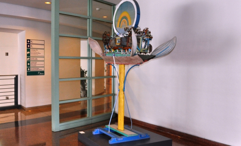 Sculpture on a pedestal of a ship with trees with wing-like oars under a rainbow in a circle