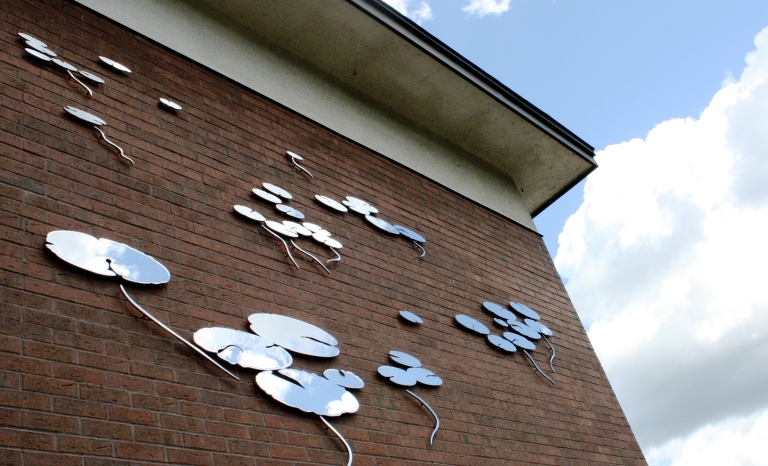 Metal silhouettes of water lilies attached to a brick building