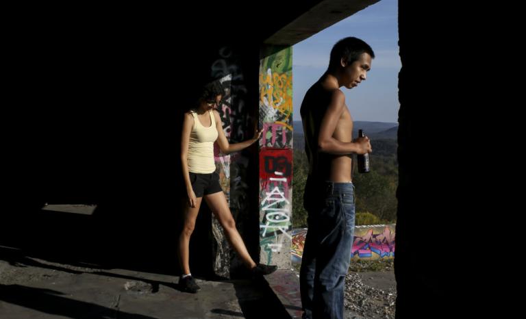 Photo of a young man and woman looking over a landscape through a graffitied doorway.