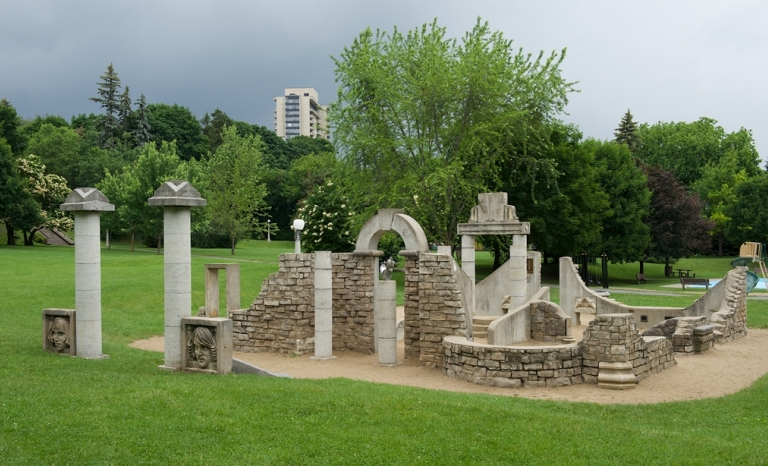 An archway, pillars and stone walls are arranged in a manner representing an ancient ruin.