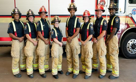 Eight career Firefighters standing in front of a fire truck