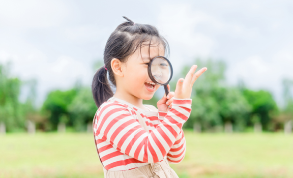 Young girl looking through magnifying glass