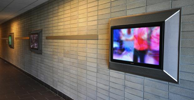 Photo d’écrans DEL installés sur un mur, chacun affichant des corps en mouvement.