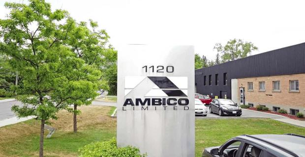 La façade de deux étages de l’usine de fabrication AMBICO et des espaces de bureaux, avec le logo de l’entreprise sur une grande enseigne en acier.
