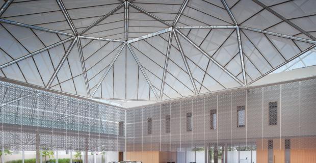 The interior atrium showcases the multi-faceted rock crystal formation and natural light of the building’s glass roof .