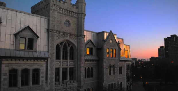 A four-storey Gothic-Revival limestone building at sunset.