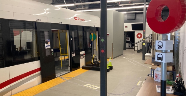 A white train car with OC Transpo logo sits in a large industrial room. 