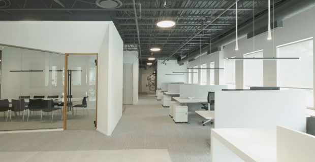 Large industrial office space with white walls, large glass doors and windows.