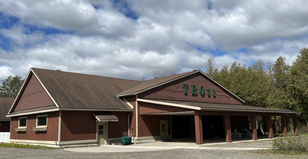 A large single-storey building with brown siding on a sunny day. A large green sign for "TRott" sits above the entrance. 