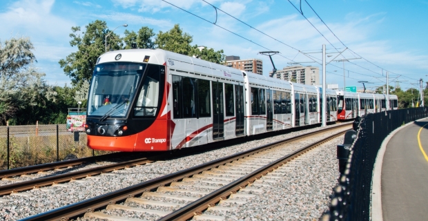 An LRT coming around a curve in the summer