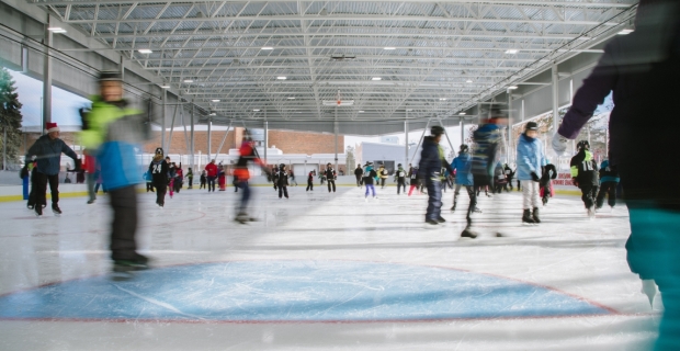 A crowd of skaters on the ice at a covered outdoor rink.